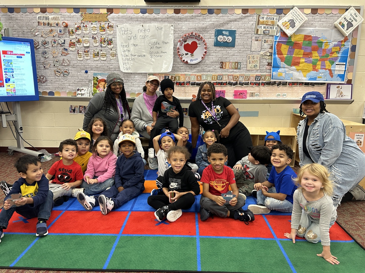 Photo shows preschool students posing for a photo with their teacher and class aides.