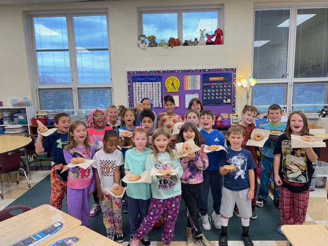 Photo of class full of students holding donuts celebrating their attendance achievement